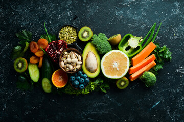 Healthy food. Vegetables and fruits. On a black wooden background. Top view. Copy space.