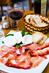 Tablesetting with a plate with prosciutto and mozzarella, natural light. Selective focus - shallow depth of field.