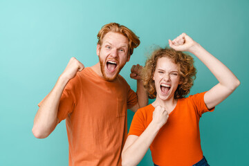 Young excited redhead couple screaming and making winner gesture