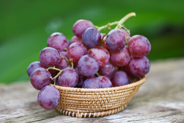 Ripe red grape in basket on wooden and natute green background , Fresh grape fruit.