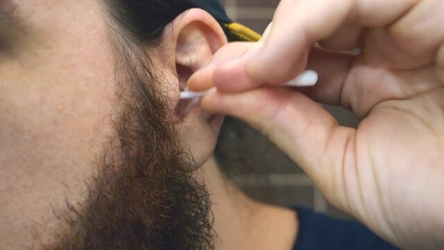 Close up footage of man cleaning with swab his ears
