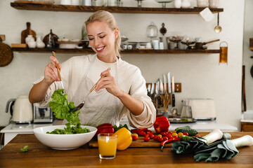 Beautiful happy woman smiling and preparing salad while making lunch