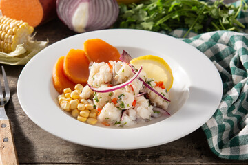 Traditional peruvian ceviche with fish, sweet potato, corn and vegetables on wooden table