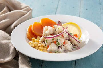 Traditional peruvian ceviche with fish, sweet potato, corn and vegetables on wooden table