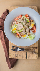 Lettuce and croutons topped with shredded cheese, Cezar salad on white plate over wooden table