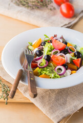Greek salad in white plate on a wooden table