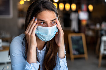 Sad, upset depressed girl, young lonely frustrated woman at coffee, suffering because of isolation, coronavirus. Person in medical protective face mask. Broken heart, virus epidemic concept