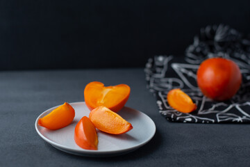 Flat lay with bright orange persimmon on black and white background