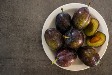 Fresh plums on a table. Water drops on juicy fruits. Close up photo of garden plums. 