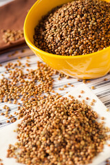 Detail photo of lots of brown lentils in natural light in a yellow bowl. Selective focus - very shallow depth of field.