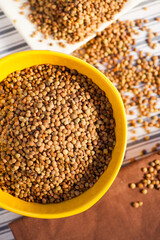 Detail photo of lots of brown lentils in natural light in a yellow bowl. Selective focus - very shallow depth of field.