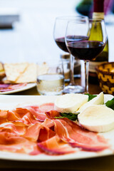Tablesetting with a plate with prosciutto and mozzarella, natural light. Selective focus - shallow depth of field.