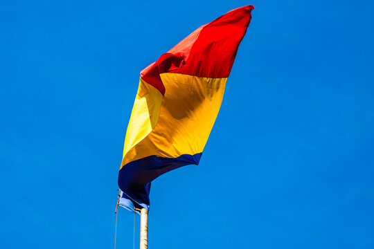 Wind blowing romanian flag on a blue clear sky.