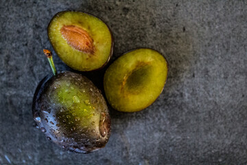 Fresh plums on a table. Water drops on juicy fruits. Close up photo of garden plums. 