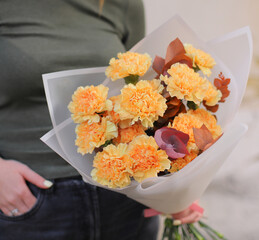 Beautiful bouquet of peach carnation and eucalyptus. Woman florist holding fresh beautiful bouquet.
