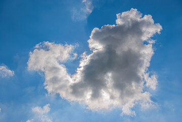 Sun Behind Clouds - The sun is hidden behind a cloud on a blue sky.