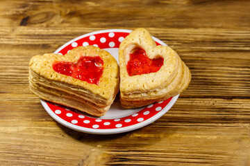 Heart shaped puff cookies with jam on a wooden table. Dessert on Valentine`s Day