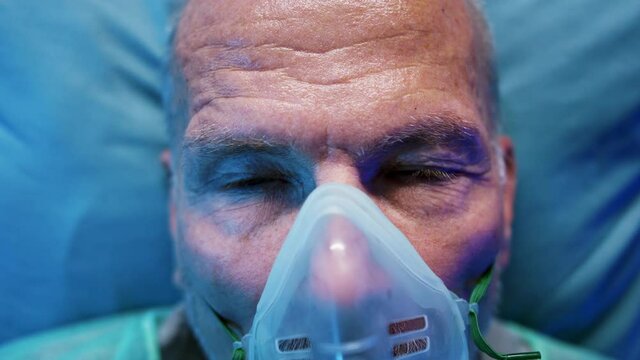 Close-up of covid-19 patient with oxygen mask in bed in hospital, coronavirus concept.