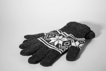 Gray knitted gloves with a white Christmas pattern on a white background. Christmas and New Year concept.