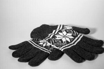 Gray knitted gloves with a white Christmas pattern on a white background. Christmas and New Year concept.