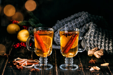 Glass cup of hot ginger tea with lemon and honey on dark wooden table. Sliced lemons on a chopping stone board