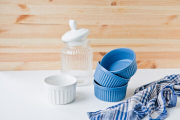 Fototapeta na wymiar Set of ceramic dishes and blue towel: small plates and glass jar