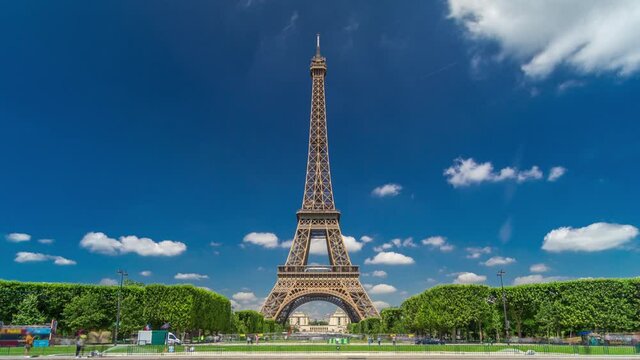 Eiffel Tower on Champs de Mars in Paris timelapse hyperlapse, France. Blue cloudy sky at summer day with green lawn and fountain