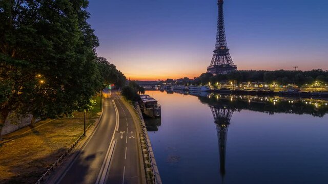 Eiffel Tower and the Seine river night to day transition timelapse before sunrise, Paris, France. Morning view from Bir-Hakeim bridge with reflections on water