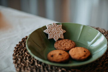 Christmas decorations. Green plate with Christmas gingerbread cookies. Decoration of festive table for christmas eve. Festive dish for new year eve.