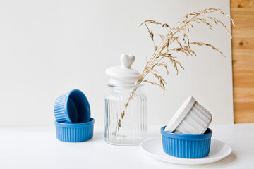 Set of ceramic dishes: small plates and glass jar on wooden background