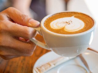 cappuccino, hands hold a cup of cappucino.