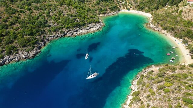 Aerial drone video of turquoise heart shaped paradise sandy beach and bay of Sarakiniko a safe sail boat anchorage in Ithaki or Ithaca island, Ionian, Greece