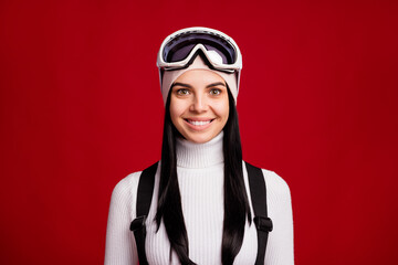 Portrait of young attractive smiling positive girl snowboarder on winter vacation isolated on red color background