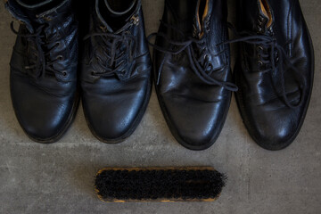 Pair of black leather retro shoes and wooden shoe brush on grey background with copy space. 
