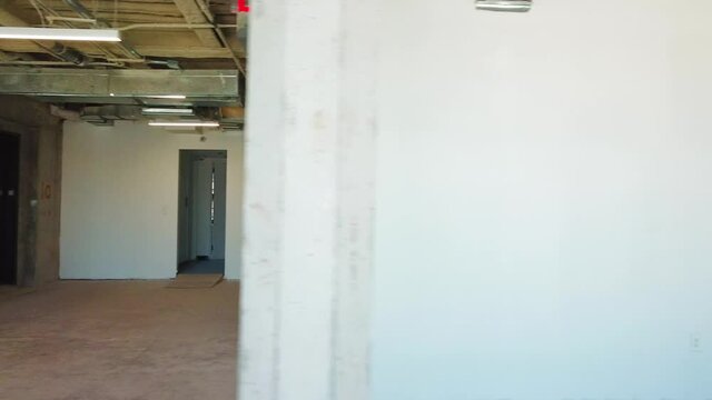 Interior view of an empty, unfinished office space that is under construction inside a large brick building.