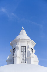 White tower with catholic cross on top in the roof of the Cathedral in Leon city, Nicaragua. Blue sky with copy space.