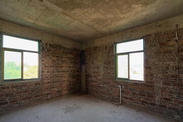 A room in a rough house under construction, with a red brick concrete structure