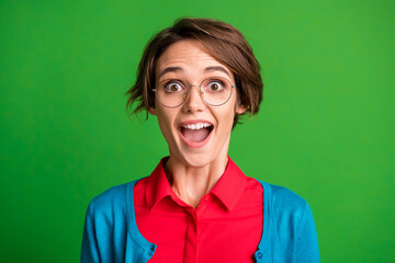 Portrait of young attractive smiling excited shocked girl with open mouth wear glasses isolated on green color background