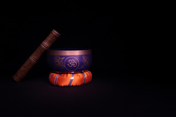 Tibetan bowl in low key on black background and orange base