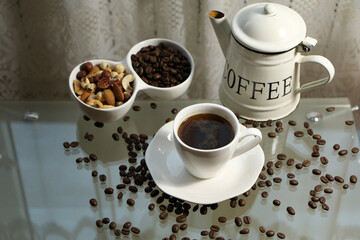 Coffee in a white cup and a white coffee pot on a glass table .