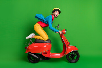 Obraz na płótnie Canvas Full size profile side photo of young excited happy girl look camera ride red moped fast isolated on green color background