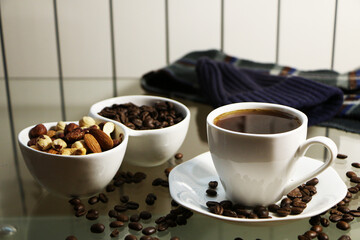 Cup of coffee and coffee beans on a glass table. The concept of home comfort and warmth.