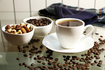 Cup of coffee and coffee beans on a glass table. The concept of home comfort and warmth.