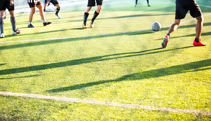Soccer player silhouette against sunlight on green artificial grass football fields with blurry...