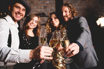 Enjoying New Year party. Group of beautiful young people in Santa hats dancing and looking happy