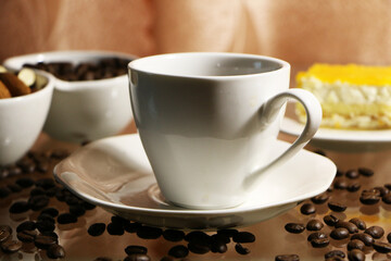 Cup of coffee and coffee beans on a glass table. The concept of home comfort and warmth.