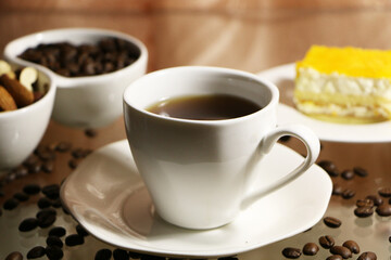 Fototapeta premium Cup of coffee and coffee beans on a glass table. The concept of home comfort and warmth.