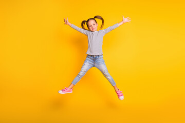 Fototapeta na wymiar Full size photo of young happy positive little girl child kid jump raise hands up isolated on yellow color background
