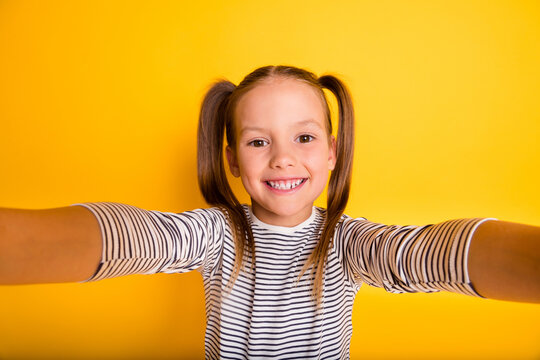 Portrait of young cheerful positive smiling little girl child kid make selfie isolated on yellow color background