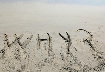Big WHY text written on the sand of the beach